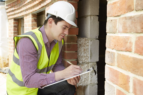 Home Inspector by Brick Foundation with Clipboard Taking Notes