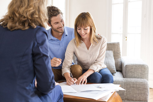 Image of couple signing contract with Real Estate Agent