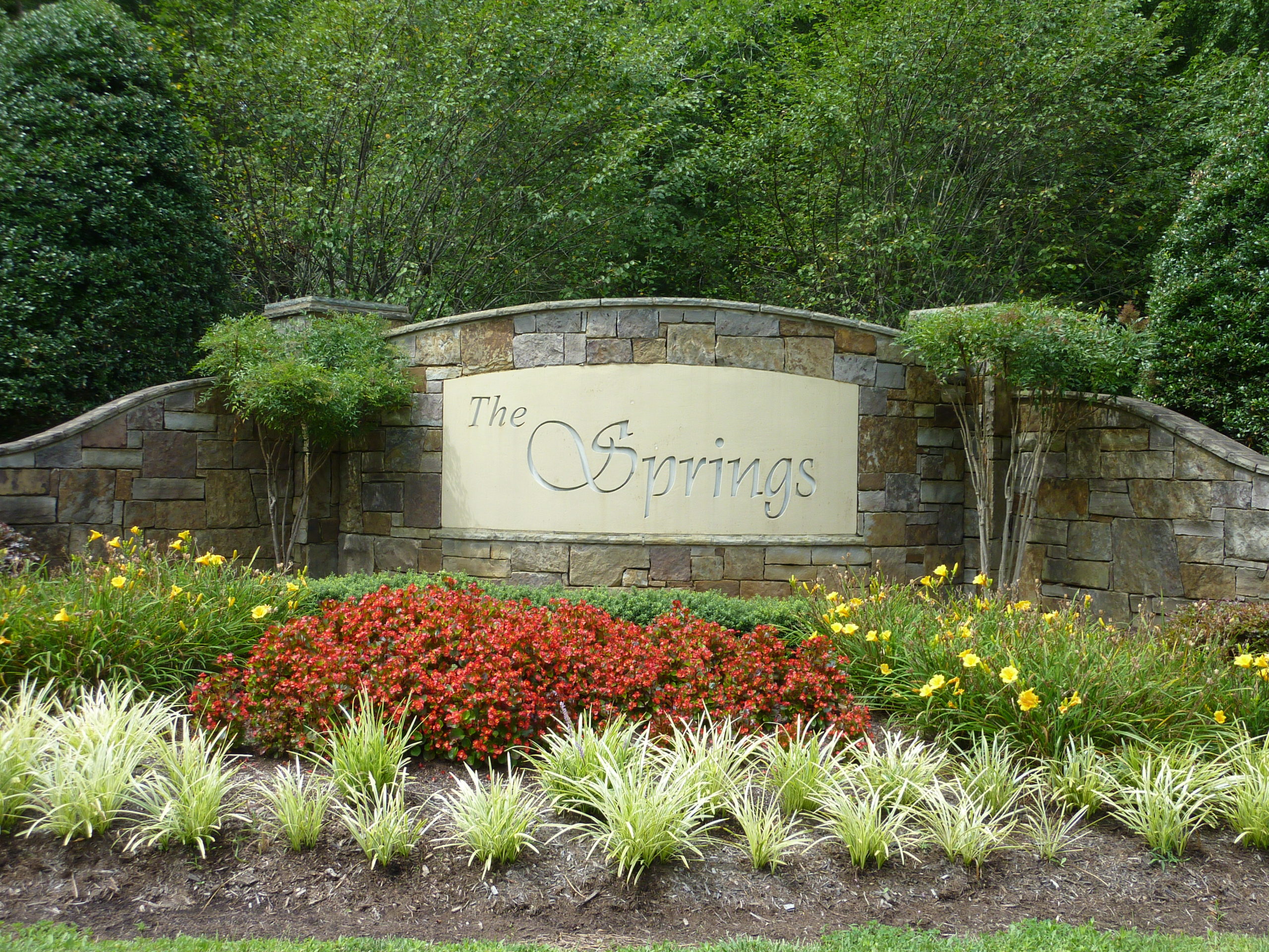 Stone entrance of The Springs at High Rock Lake with flower display in front